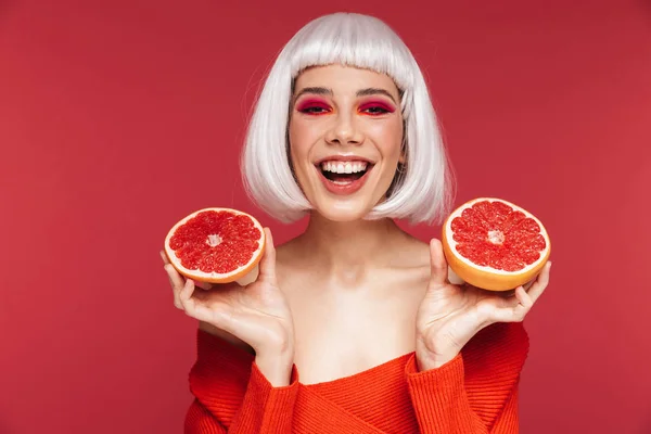 Veselá krásná mladá žena izolována pozadí červené zdi drží grapefruitu. — Stock fotografie