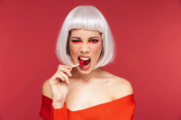 Bela jovem mulher isolado sobre vermelho parede fundo segurando pirulito doce . — Fotografia de Stock