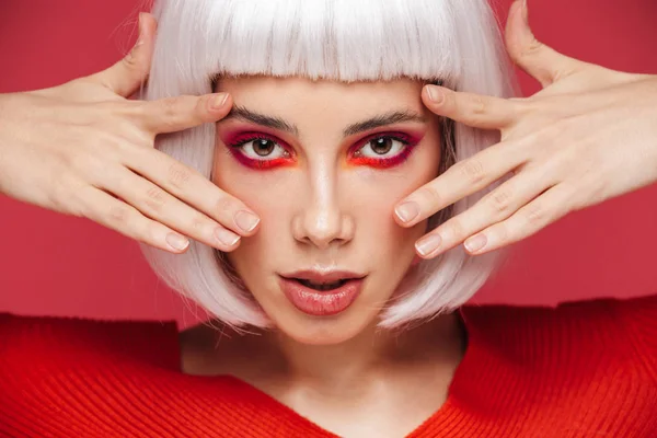 Schöne junge Frau isoliert über roter Wand Hintergrund mit hellem Make-up posiert. — Stockfoto