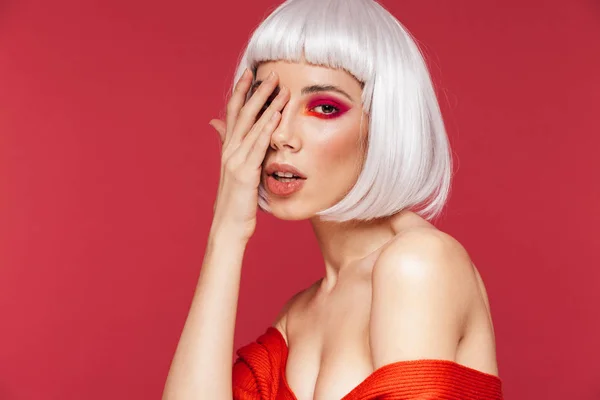 Schöne junge Frau isoliert über roter Wand Hintergrund mit hellem Make-up posiert. — Stockfoto
