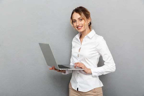 Foto de una mujer inteligente en ropa formal de pie y la celebración de la computadora portátil — Foto de Stock