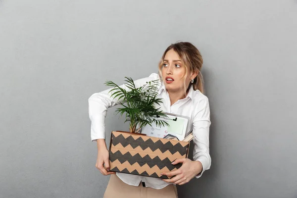 Triste mujer de negocios aislada sobre fondo de pared gris caja con planta y documentos . — Foto de Stock