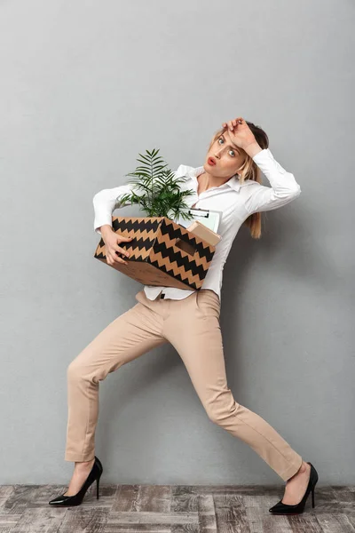 Triste mujer de negocios aislada sobre fondo de pared gris caja con planta y documentos . — Foto de Stock