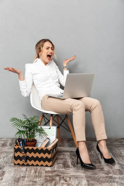 Retrato de mulher estressada usando laptop enquanto sentado na cadeira w — Fotografia de Stock