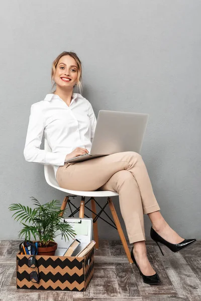 Retrato de mulher sorridente usando laptop enquanto sentado na cadeira wi — Fotografia de Stock