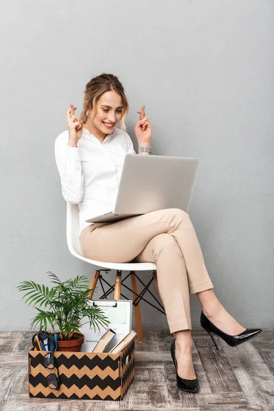 Retrato de mulher alegre usando laptop enquanto sentado na cadeira sagacidade — Fotografia de Stock