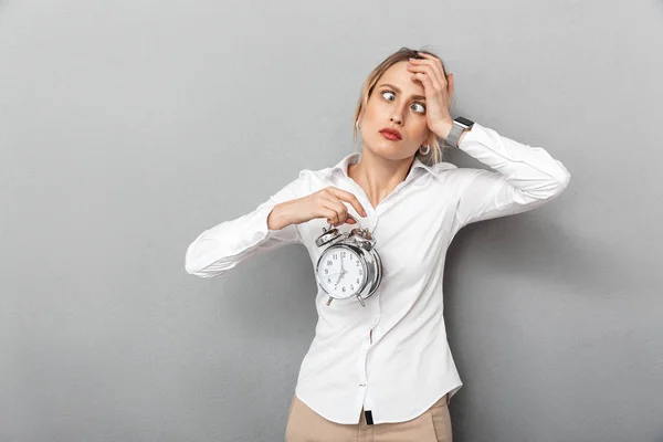 Retrato de una mujer de negocios sorprendida sosteniendo el despertador en el off — Foto de Stock