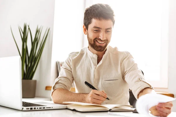 Imagen del alegre hombre de negocios de 30 años con camisa blanca trabajando con — Foto de Stock