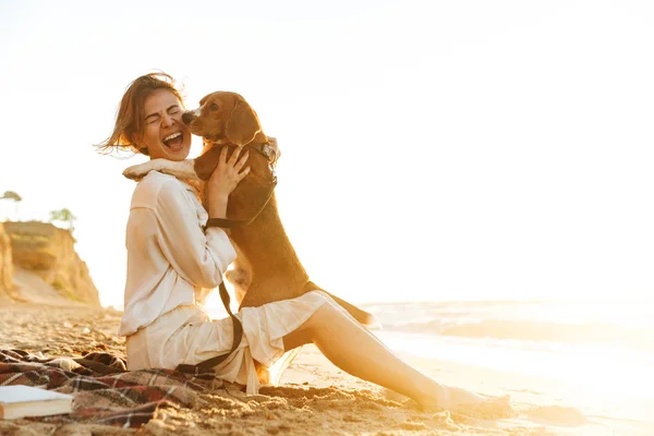 Image of cheerful woman 20s hugging her dog, while sitting on sa — Stock Photo, Image