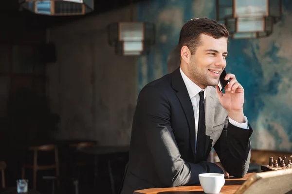 Heureux jeune homme d'affaires assis dans un café parlant par téléphone mobile . — Photo