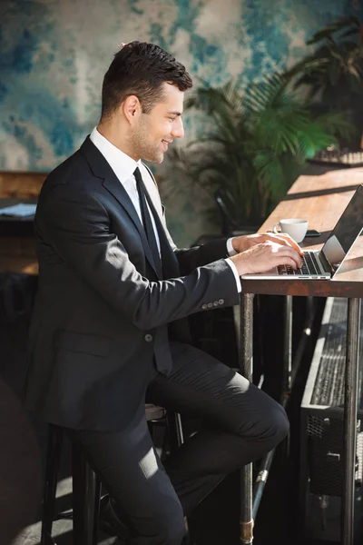 Beau jeune homme d'affaires en vêtements formels à l'intérieur dans le café à l'aide d'un ordinateur portable . — Photo