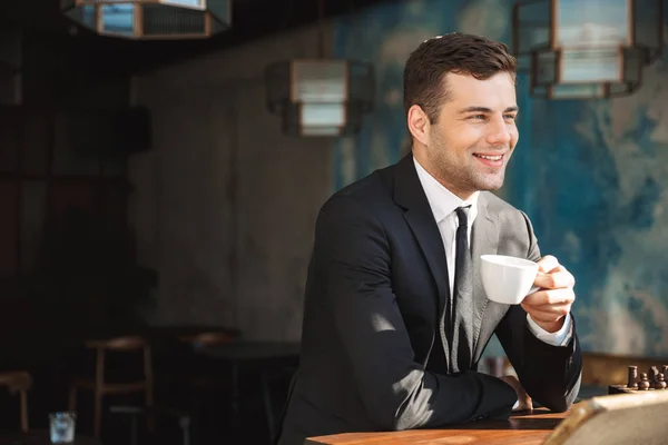 Knappe gelukkig jonge zakenman zitten in Cafe koffie drinken. — Stockfoto