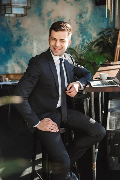 Guapo joven hombre de negocios en ropa formal en el interior de la cafetería con ordenador portátil . —  Fotos de Stock