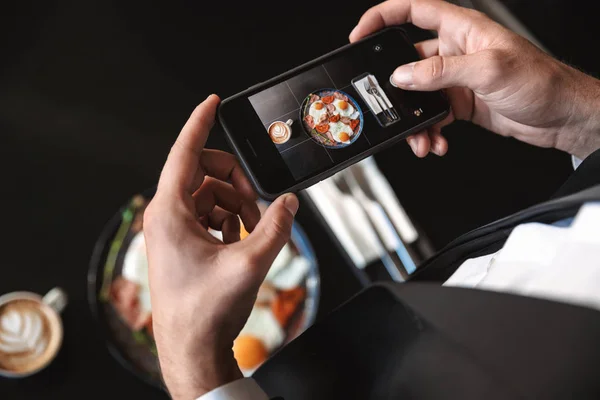 Бізнесмен, сидячи в кафе фотографії їжі по мобільному телефону . — стокове фото
