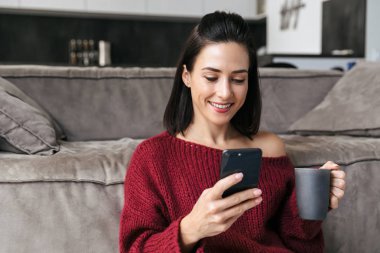 Güzel kadın kapalı içinde ev istimal hareket eden telefon kahve içme.