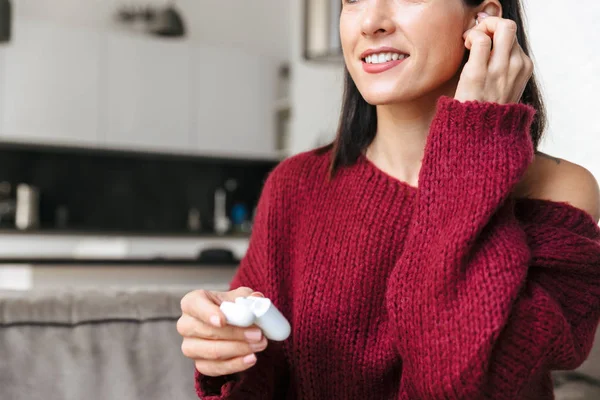 Hermosa mujer dentro de casa en el sofá escuchando música con auriculares . — Foto de Stock