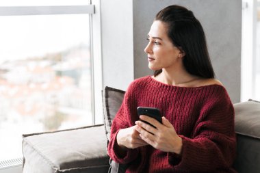 Cep telefonu kullaranarak kanepe kapalı evinde güzel kadın.