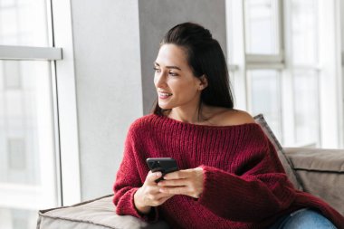 Cep telefonu kullaranarak kanepe kapalı evinde güzel kadın.
