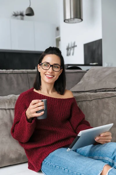 タブレット コンピューターを使用してソファの上の家で屋内での驚くべき女性. — ストック写真
