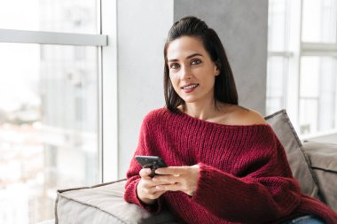 Cep telefonu kullaranarak kanepe kapalı evinde güzel kadın.