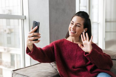Kadın kapalı cep telefonuyla konuşan Divan evinde.