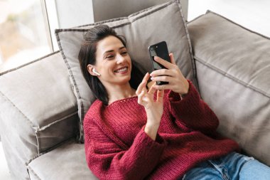 Cep telefonu kullaranarak kanepe kapalı evinde güzel kadın.