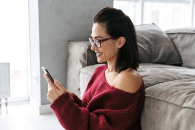 Cep telefonu kullaranarak kanepe kapalı evinde güzel kadın.