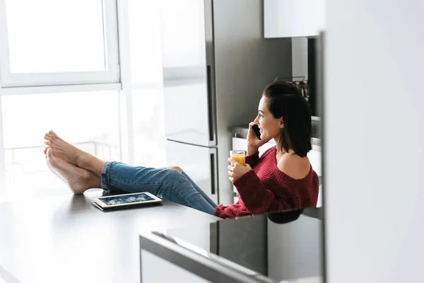 Femme à l'intérieur dans la maison à la cuisine parler par téléphone mobile . — Photo