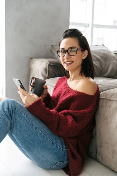 Красивая женщина в помещении дома на диване с помощью мобильного телефона . — стоковое фото