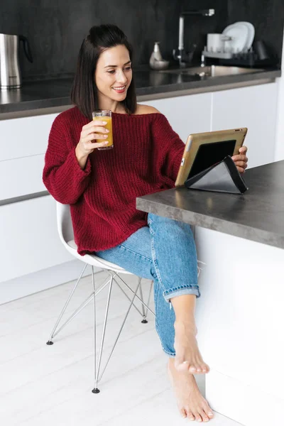 Erstaunliche Frau zu Hause in der Küche mit Tablet-Computer Saft trinken. — Stockfoto