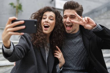 Görüntü memnun çift erkek ve kadın 20'li yaşlarda sıcak giysiler, tak