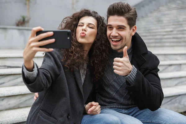 Imagen de pareja excitada hombre y mujer de 20 años en ropa de abrigo, takin — Foto de Stock