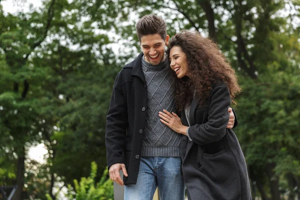 Image of young couple man and woman 20s hugging, and walking thr — Stock Photo, Image