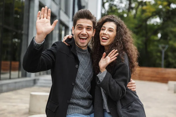 Photo of smiling couple man and woman 20s waving hands while, st — Stock Photo, Image