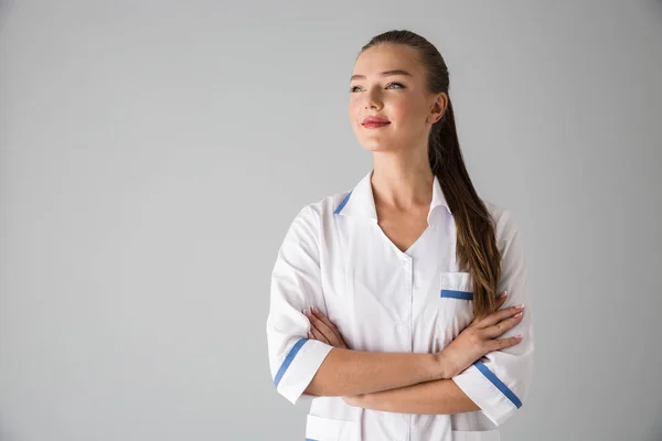 Vacker ung kvinna kosmetolog läkare isolerade över grå vägg bakgrund. — Stockfoto