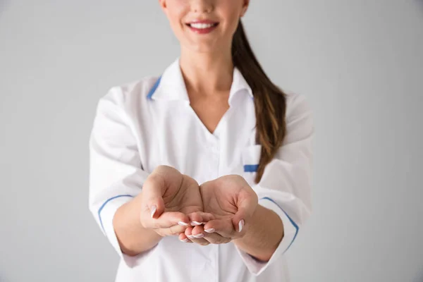 Mooie jonge vrouw schoonheidsspecialist arts geïsoleerd over grijs muur achtergrond weergegeven: een handen. — Stockfoto