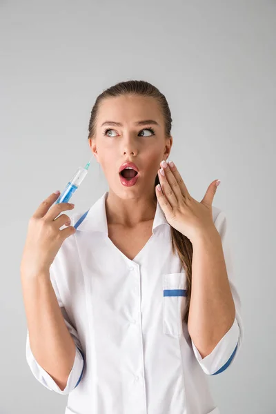 Belle jeune femme cosmétologue médecin isolé sur fond de mur gris tenant la seringue d'injection . — Photo