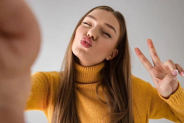 Heureuse jeune femme isolée sur fond de mur gris prendre un selfie par caméra . — Photo