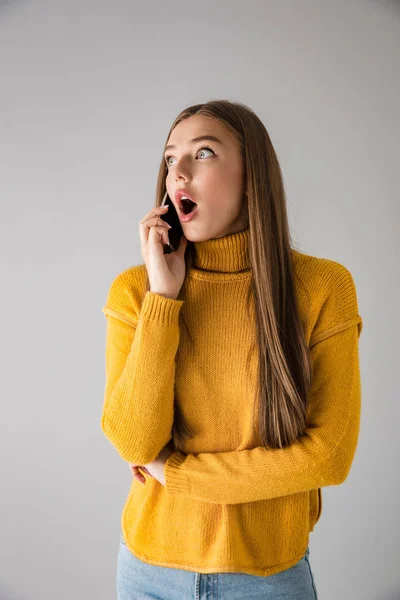 Glückliche junge Frau isoliert über grauem Wandhintergrund im Gespräch per Mobiltelefon. — Stockfoto