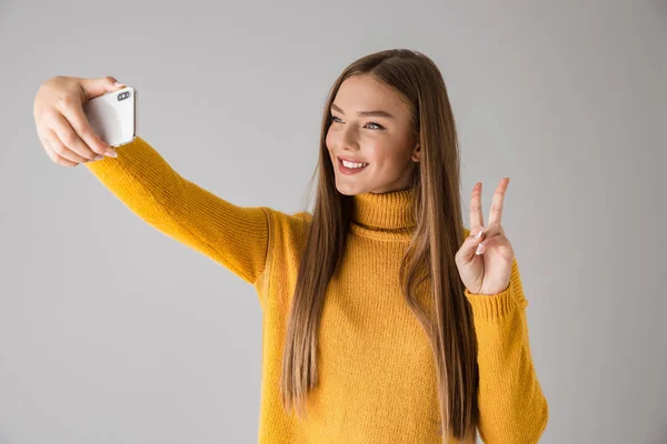 Ευτυχισμένη γυναίκα απομονωμένη αναλάβει φόντο γκρίζο τοίχο μια selfie από κινητό τηλέφωνο. — Φωτογραφία Αρχείου