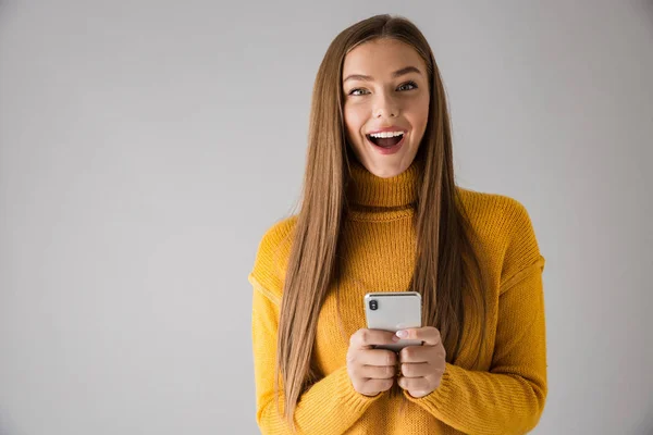 Šťastná mladá žena izolována šedá stěna pozadí pomocí mobilního telefonu. — Stock fotografie