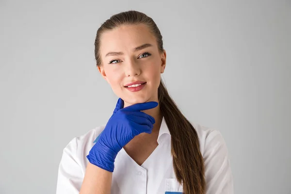 Bella giovane donna cosmetologo medico isolato su sfondo grigio parete . — Foto Stock