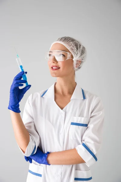 Bella giovane donna cosmetologo medico isolato su sfondo grigio parete tenuta siringa per iniezione . — Foto Stock