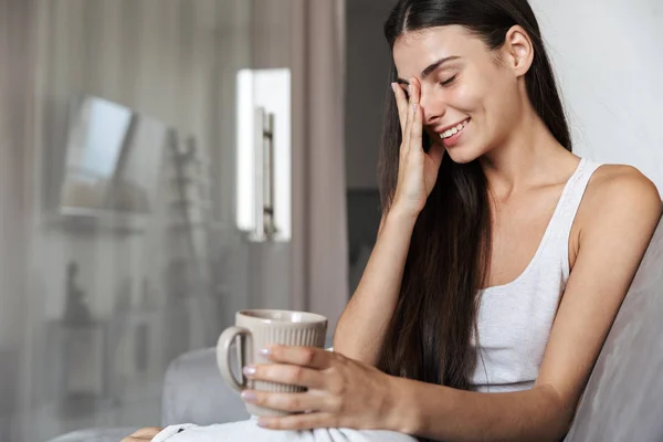 Vacker ung kvinna som är avkopplande på en soffa hemma — Stockfoto