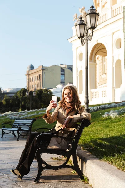 Glückliche junge schöne Frau, die draußen spaziert, macht ein Selfie mit dem Handy. — Stockfoto