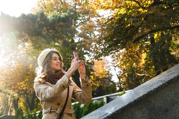 Aufgeregte junge schöne Frau im Freien am Straßenpark macht ein Selfie mit dem Handy. — Stockfoto