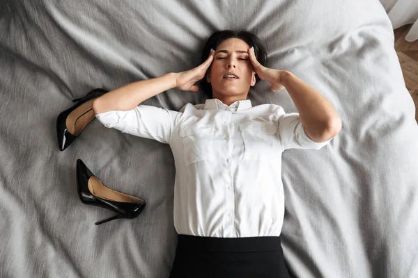 Belle femme d'affaires fatiguée dans la chambre à coucher à l'intérieur à la maison se trouve sur le lit . — Photo