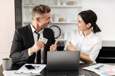 Yakışıklı iş adamı iş belgeleri ve kredi kartı dizüstü bilgisayarı ile onun meslektaşım kadınla kapalı.