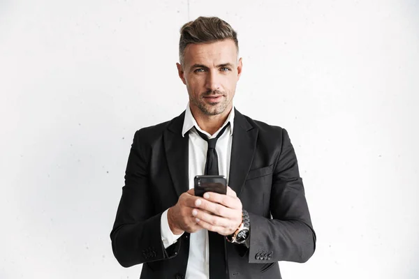 Handsome business man posing isolated over white wall background using mobile phone. — Stock Photo, Image