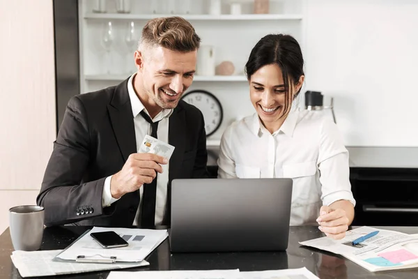 Hombre de negocios guapo trabajo en interiores con su colega mujer con documentos y computadora portátil . — Foto de Stock